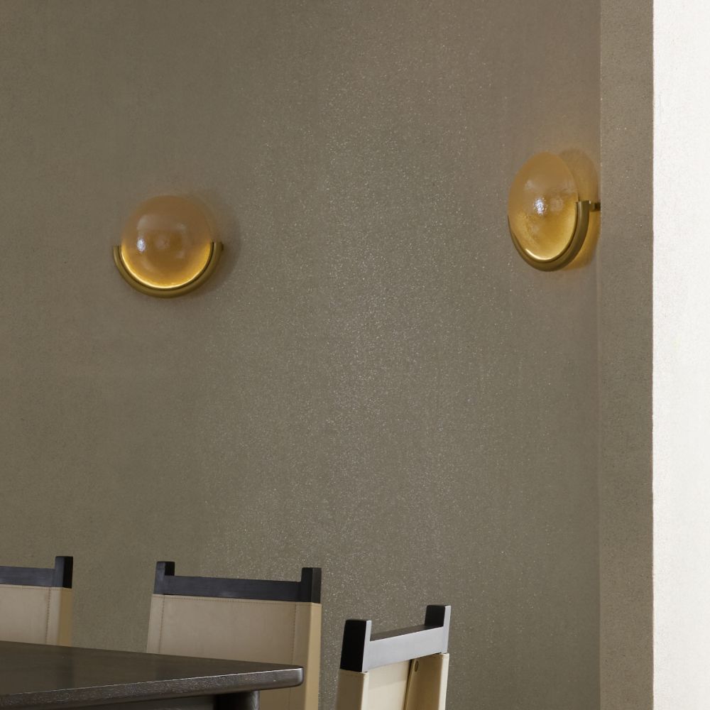 Two wall-mounted lights on a beige wall with a dining table and chairs in the foreground.