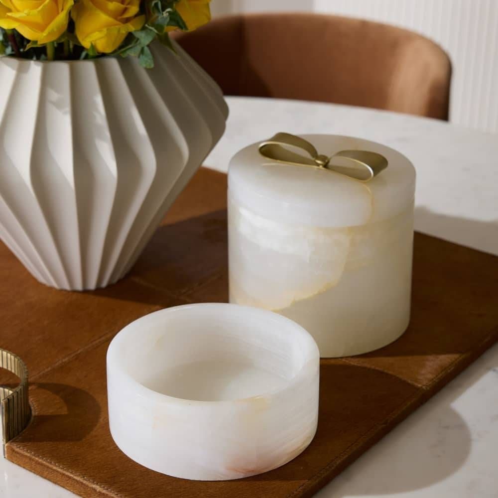 Decorative items including a vase with yellow flowers, two marble candle holders, and a wooden tray on a table.