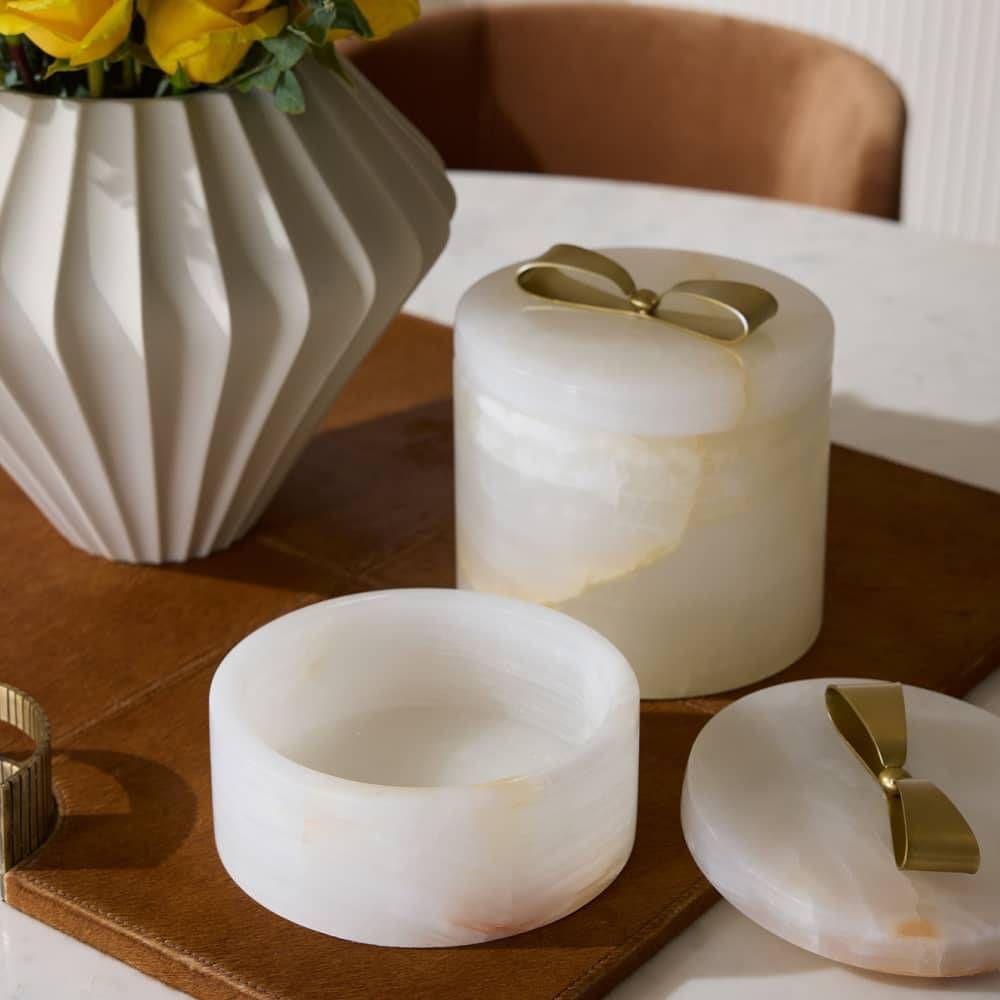 Set of marble containers with gold accents on a wooden surface.