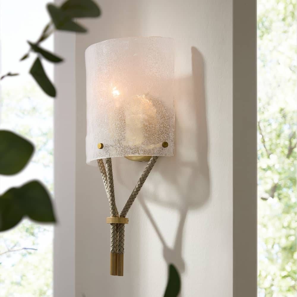 Wall-mounted light fixture with textured glass shade and rope detail on a white wall.