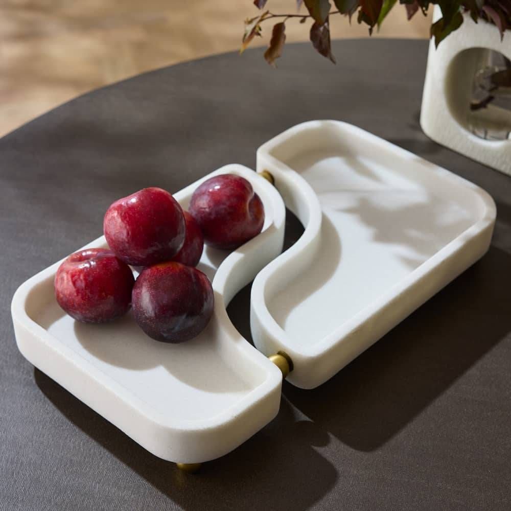 White ceramic fruit bowl with red grapes on a dark surface