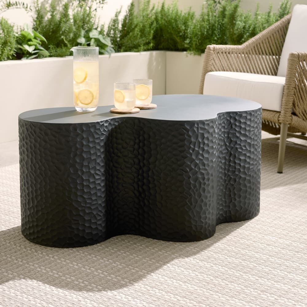 Black textured coffee table with candles on a patio setting