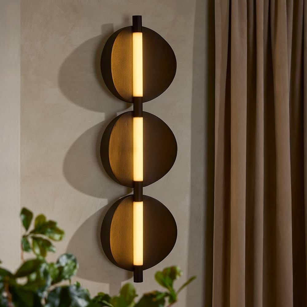 Modern wall sconce with three spherical lights on a neutral wall.