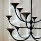 Black chandelier with multiple light bulbs against a white paneled wall.