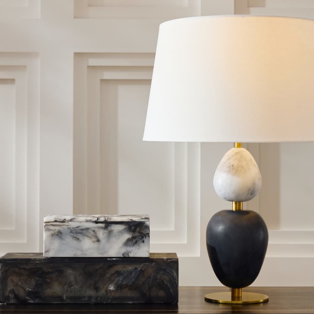 Decorative lamp with marble base and shade on a wooden surface.