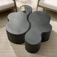 Modern black wicker coffee table with a candle on a textured floor.