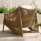 Woven chair with a white cushion on a patio with plants in the background