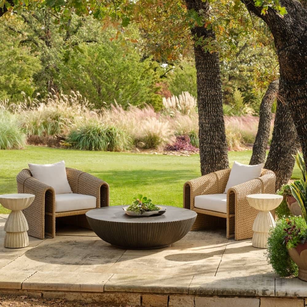 Outdoor patio setting with wicker chairs, coffee table, and side tables on a stone patio.