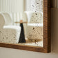 Speckled mirror with wooden frame on a neutral background