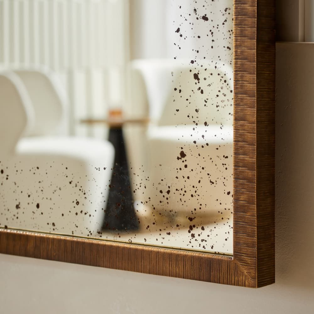 Speckled mirror with wooden frame on a neutral background