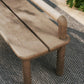 Wooden bench with a textured surface on a woven mat