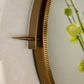 Gold wall clock with a decorative spike on a light background