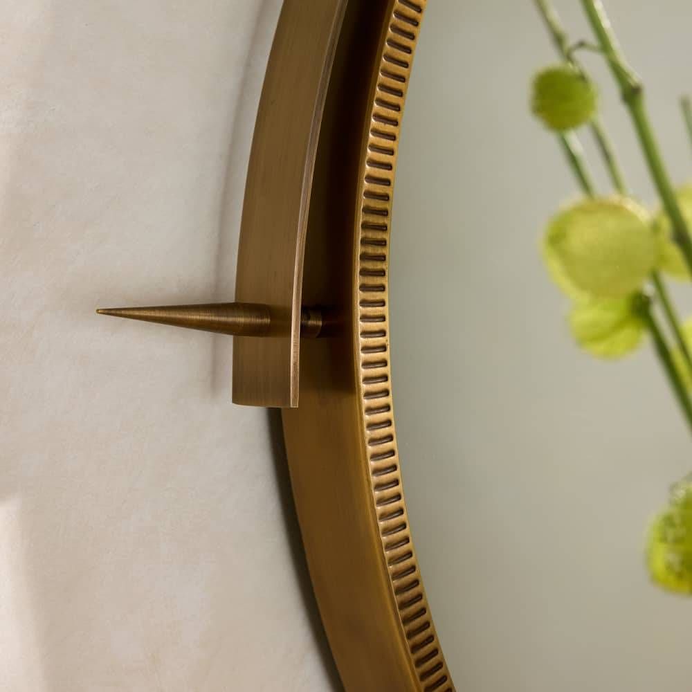 Gold wall clock with a decorative spike on a light background