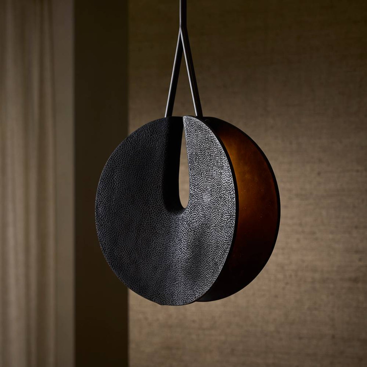Round pendant light with textured surface on a neutral background