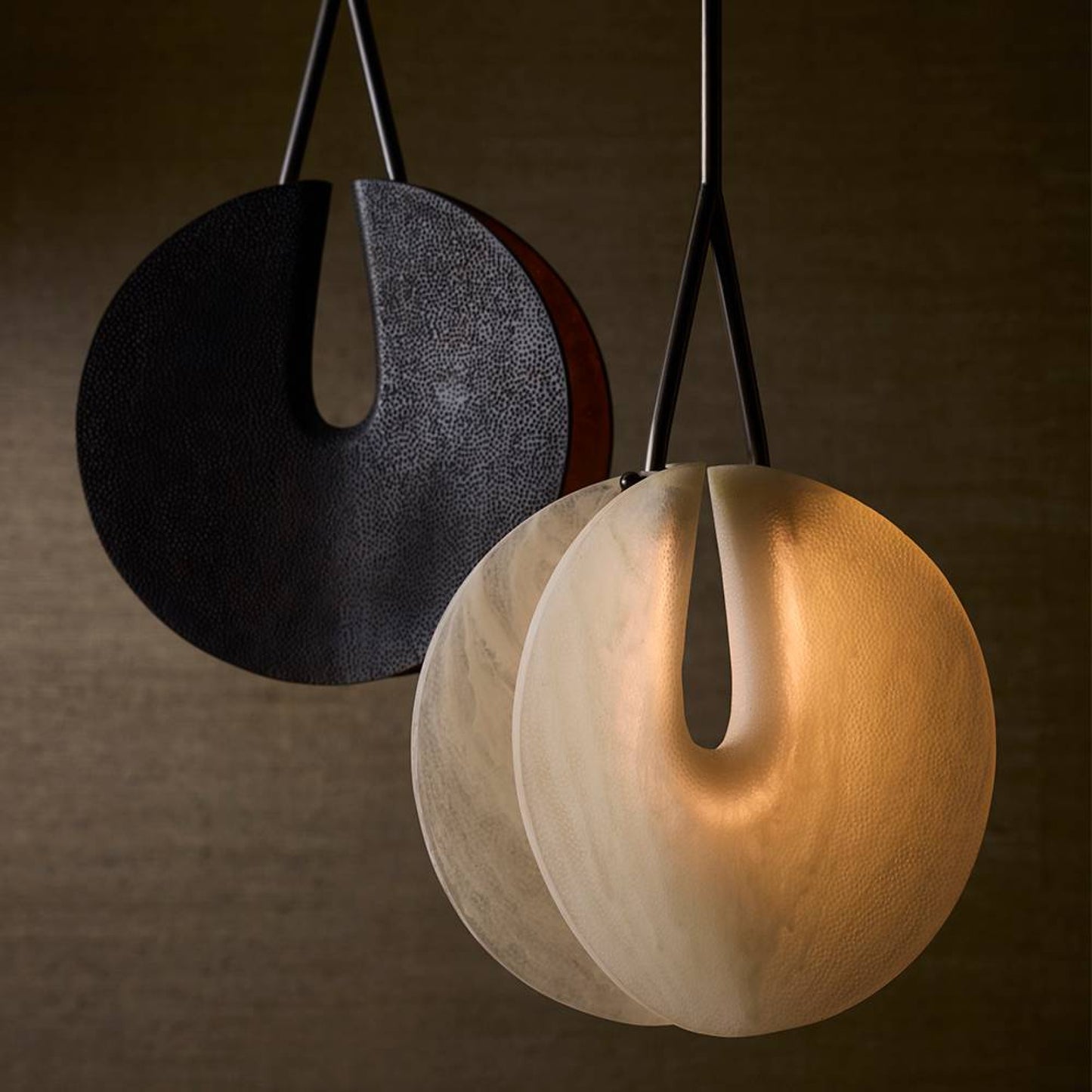 Two modern pendant lights, one black and one beige, on a dark background.