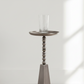 Decorative candle holder with a glass candle on a white floor and light gray wall.