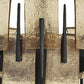 Decorative wall art with black cylindrical elements on a textured beige background
