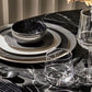 Dinnerware set with black and white crocodile-patterned bowls on a marble table.
