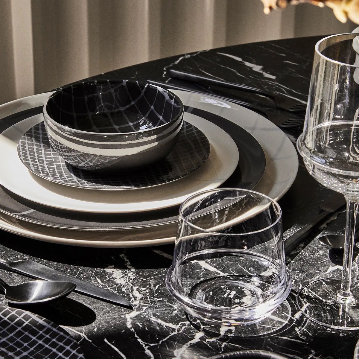 Dinnerware set with black and white crocodile-patterned bowls on a marble table.