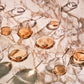 Multiple glasses of rose gold liquid arranged on a reflective surface