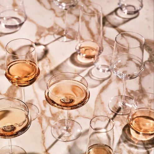 Multiple wine glasses filled with a amber-colored liquid on a marble surface.