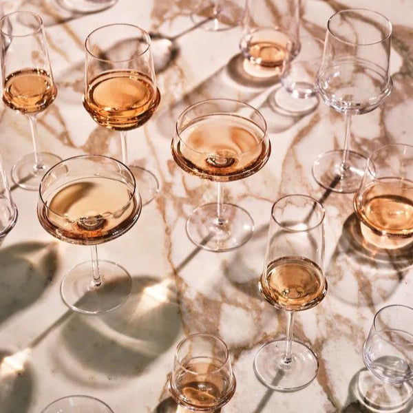 Multiple wine glasses filled with a golden liquid on a marble surface