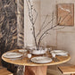 Dining table set with plates, glasses, and a decorative branch in a modern kitchen.