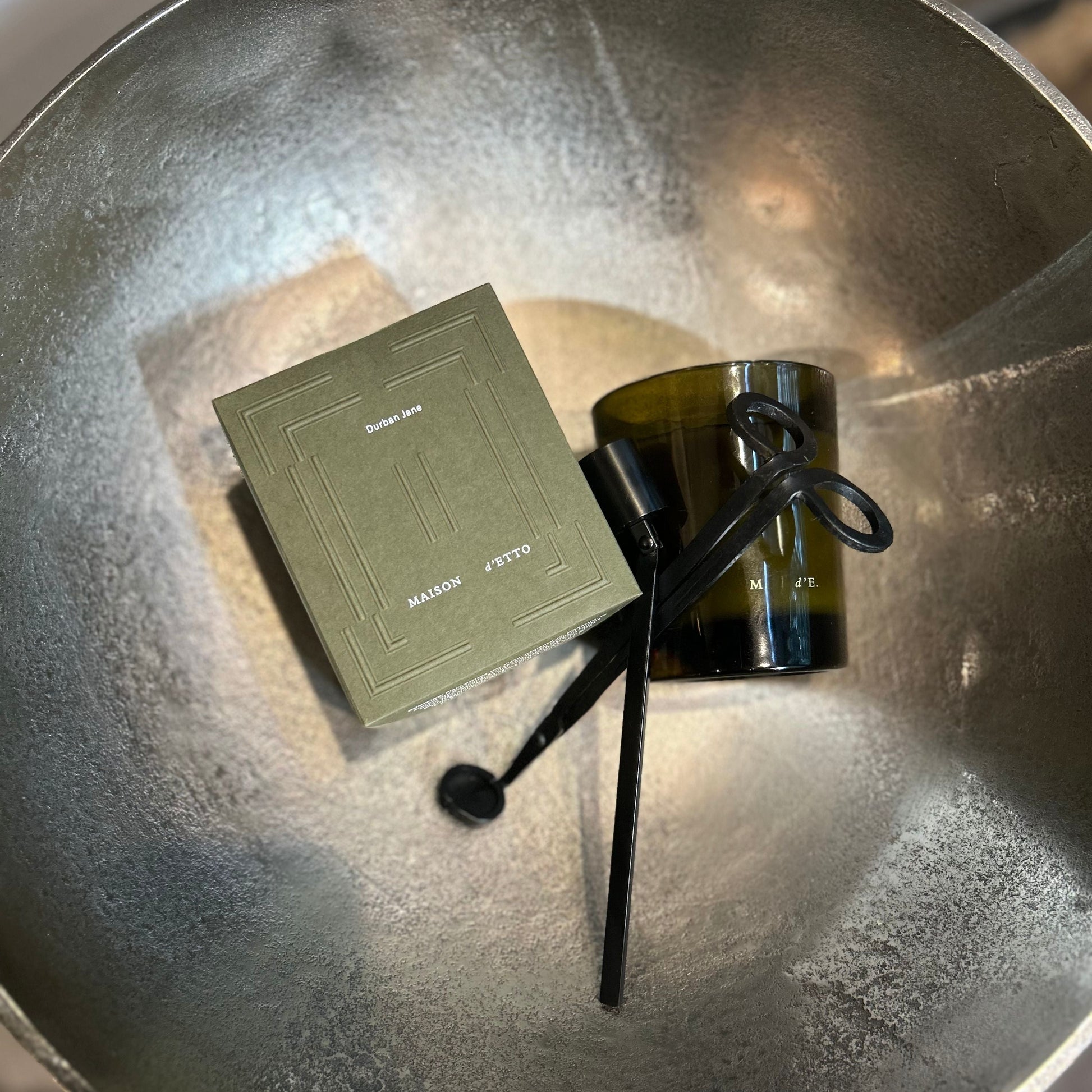 Green box, black candle, and black candle stick on a metallic surface
