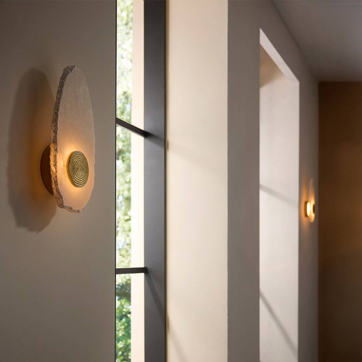 Modern wall sconce on a white wall with a window in the background
