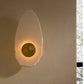 Wall-mounted light fixture with a textured design on a beige wall
