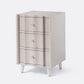 Beige three-drawer nightstand with white legs on a light gray background