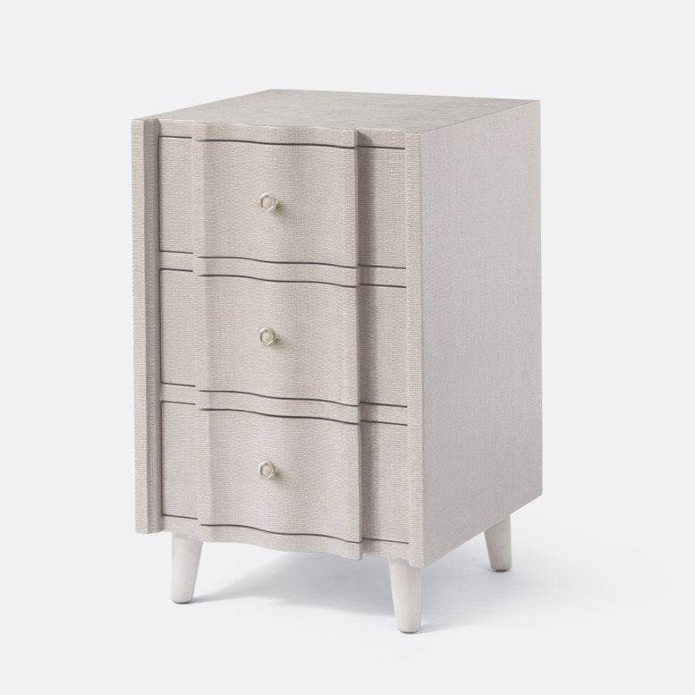 Beige three-drawer nightstand with white legs on a light gray background