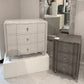 Two gray dressers with decorative handles in a showroom setting.