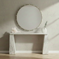 Round mirror with decorative lights on a marble console table in a bright room.