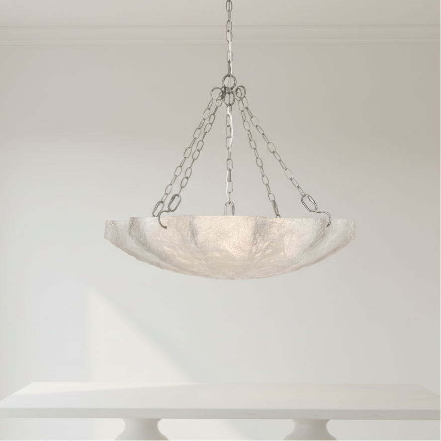 Chandelier with marble-like shade hanging against a white wall