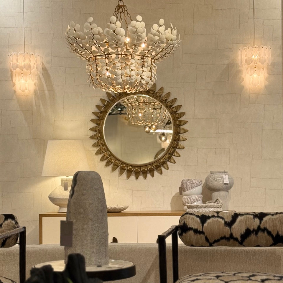 Decorative interior with a chandelier, mirror, and chairs.