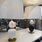 Two table lamps with marble-like tops on a white surface, with a reflective background.