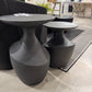 Black round tables on a stone floor with a blurred indoor background