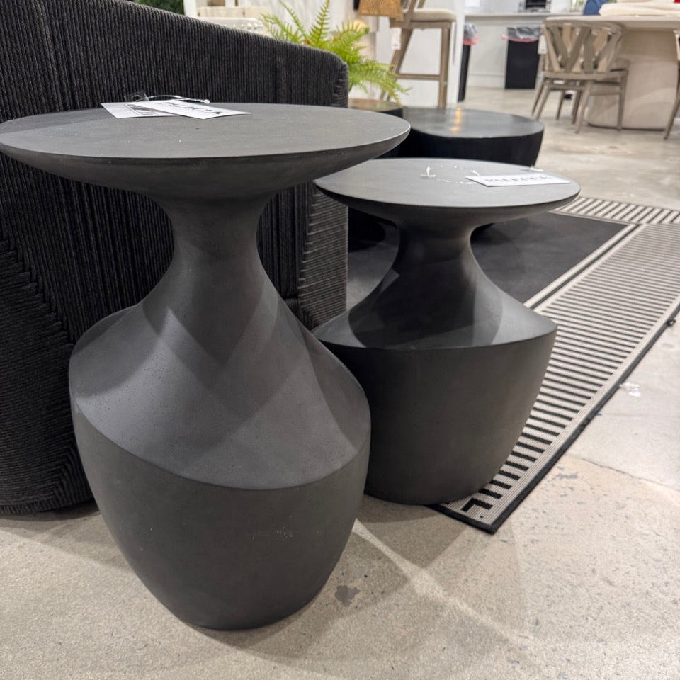 Black round tables on a stone floor with a blurred indoor background