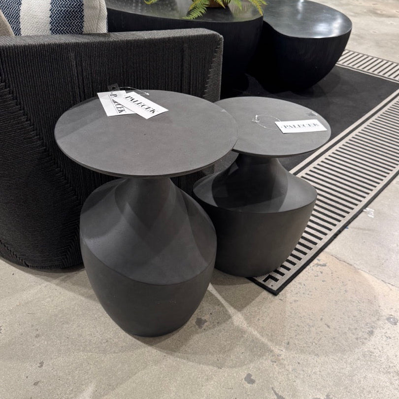 Black side tables with price tags in a showroom setting