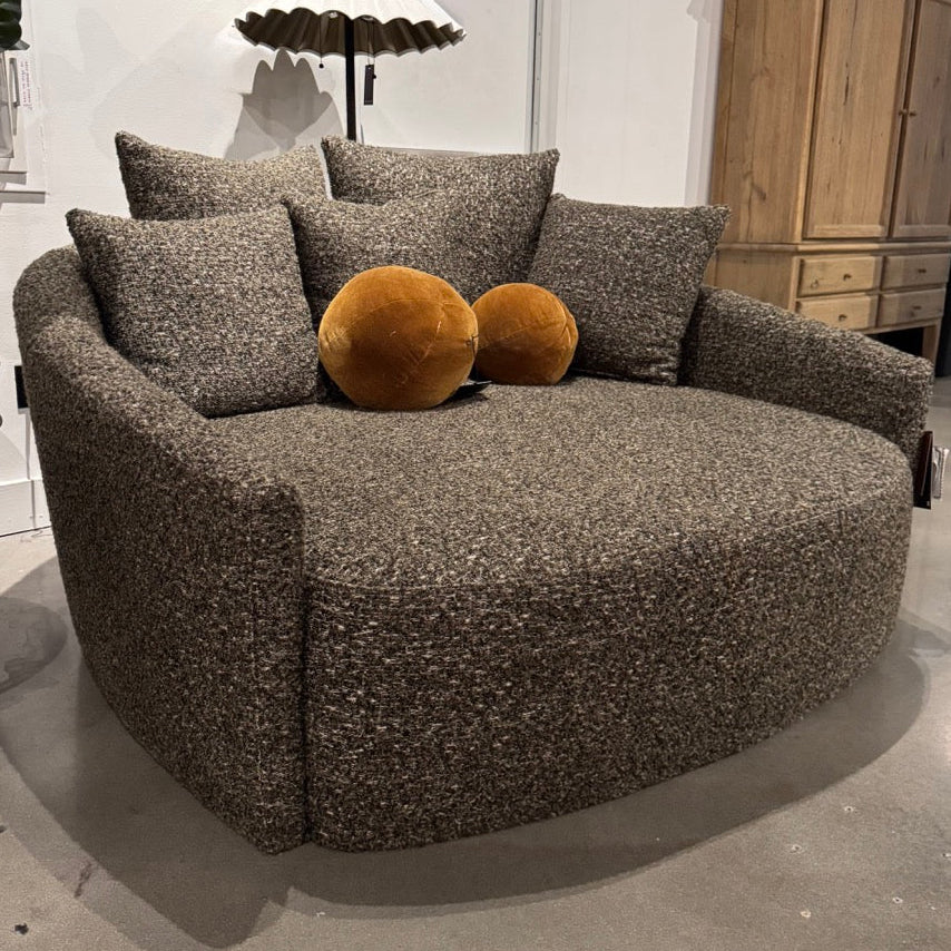 Round brown sofa with textured surface and decorative pillows in a room setting.