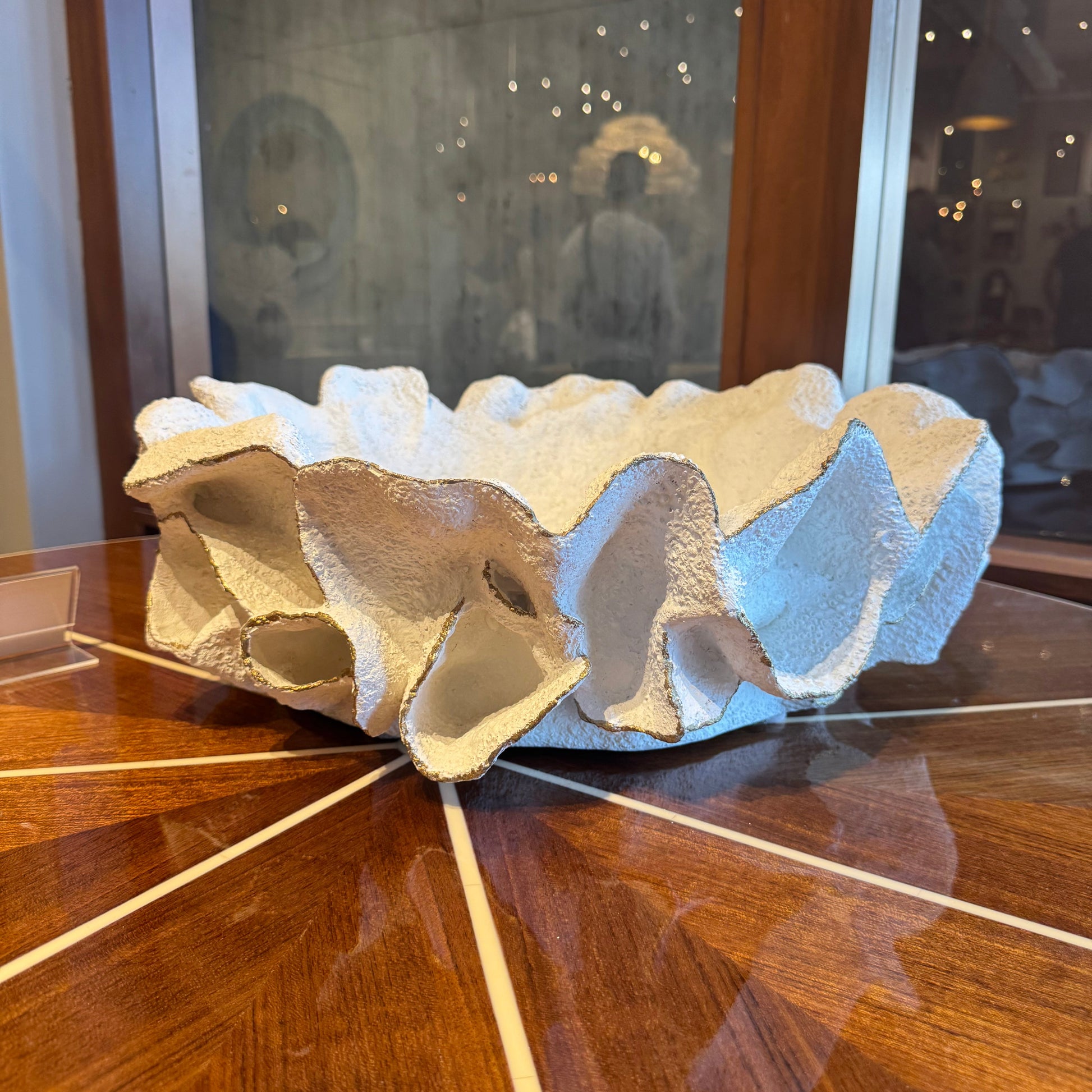 Decorative stone sculpture on a wooden surface with a reflective surface in the background