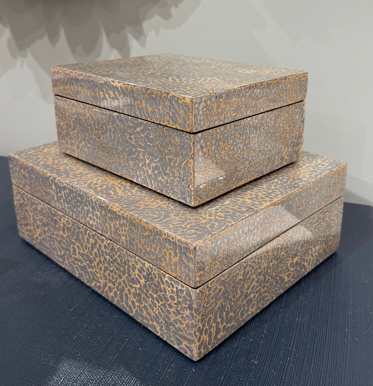 Two patterned boxes stacked on a dark surface with a gray background
