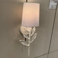 Wall-mounted light fixture with leaf design on a gray wall
