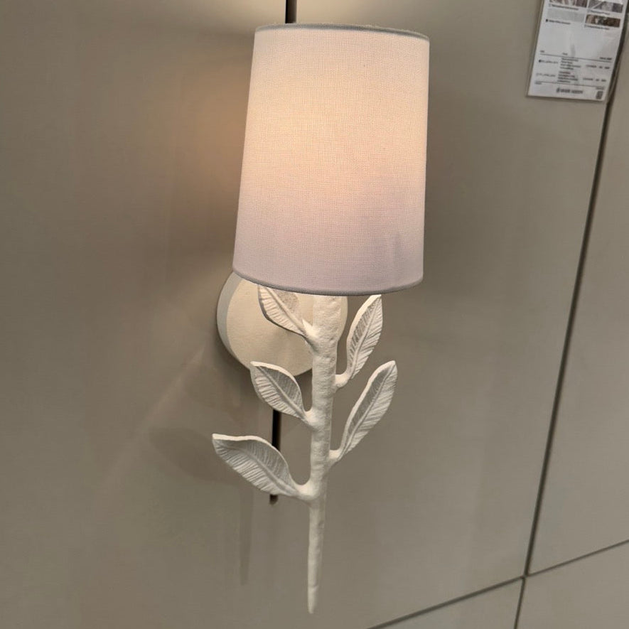 Wall-mounted light fixture with leaf design on a gray wall