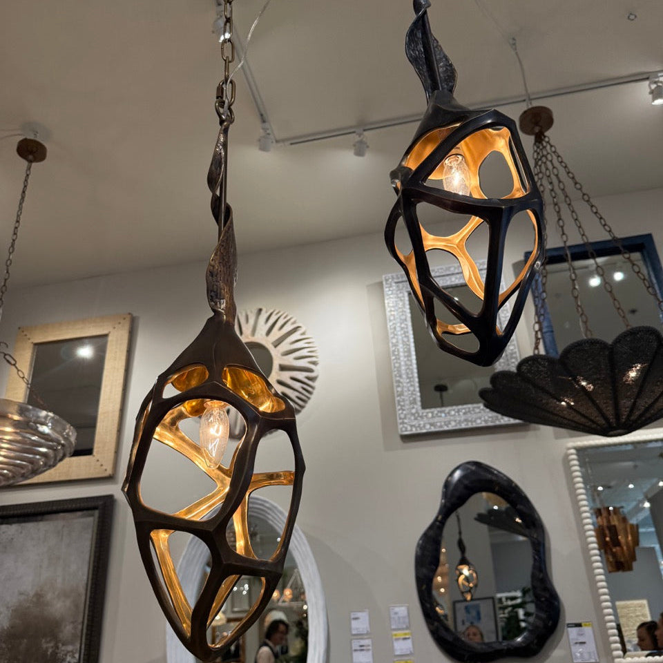 Decorative hanging lights with artistic designs in a room with mirrors and artwork on the walls.