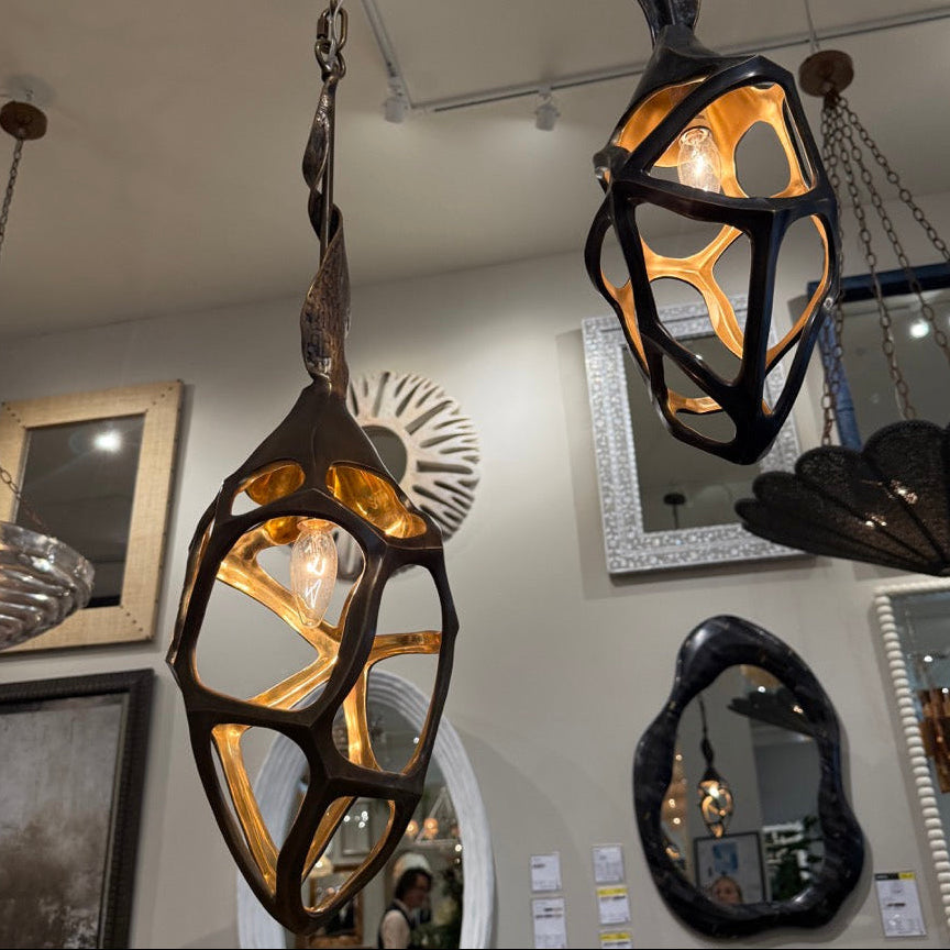 Decorative hanging lights with artistic designs in a room with mirrors and artwork on the walls.