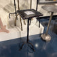 Set of vintage-style metal stools with a dark finish on a reflective surface.