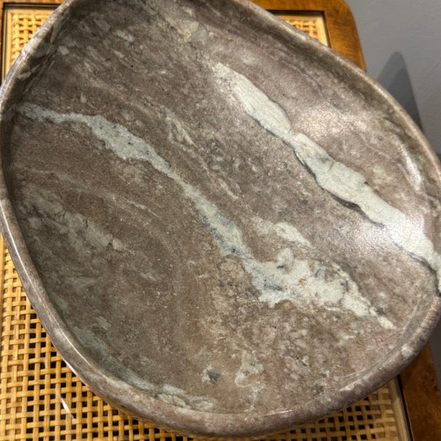Two stone bowls on a woven mat with a blurred background