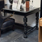 Decorative black table with intricate legs in a showroom setting
